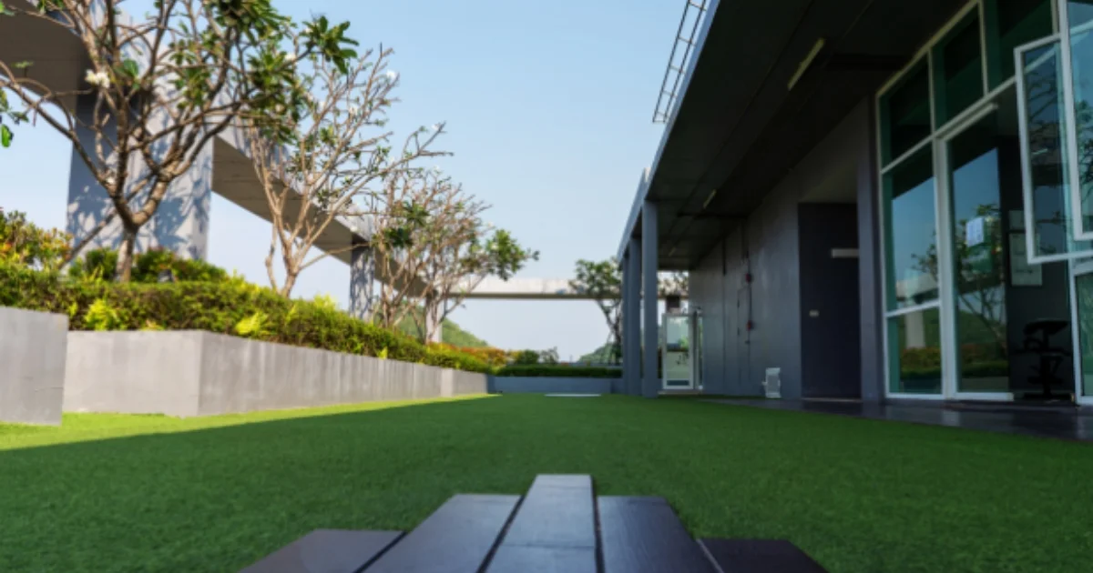 Modern side yard with synthetic grass and raised planters along a building exterior
